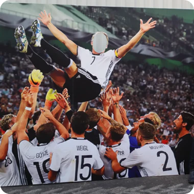 Custom photo cutout board featuring a stadium scene of a football team tossing a player into the air, with a cutout face hole on the celebrated player.